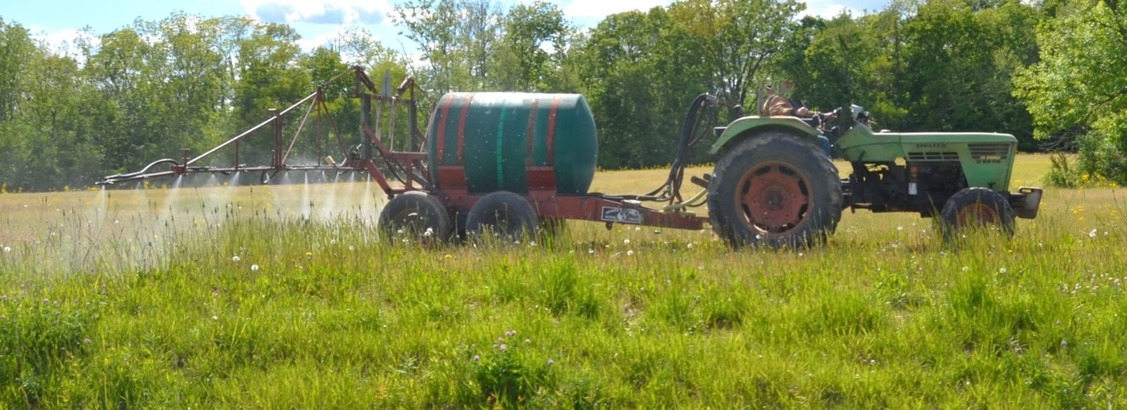 Tractor spraying a field, illustrating the Roundup settlement over glyphosate weedkiller and non-Hodgkin lymphoma claims